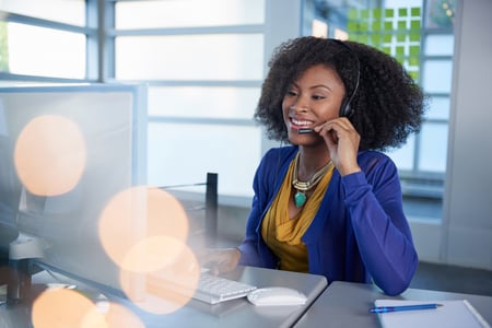 Portrait of a smiling customer service representative at the computer using headset